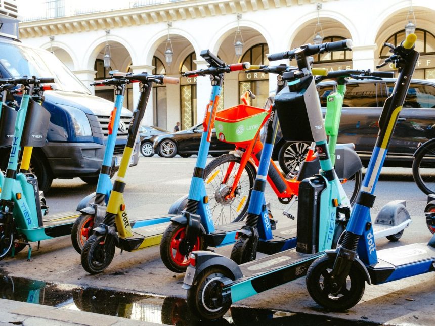 Bicicletas e patinetes elétricos estacionados juntos em uma movimentada rua urbana.