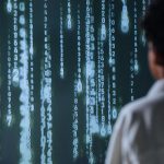 Pessoa observa números luminosos em uma tela, em representação de tecnologia e processamento de dados.