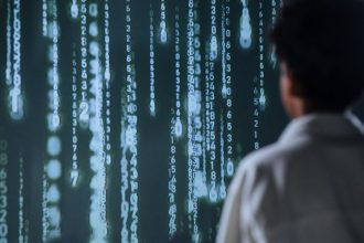 Pessoa observa números luminosos em uma tela, em representação de tecnologia e processamento de dados.