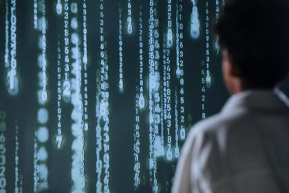 Pessoa observa números luminosos em uma tela, em representação de tecnologia e processamento de dados.