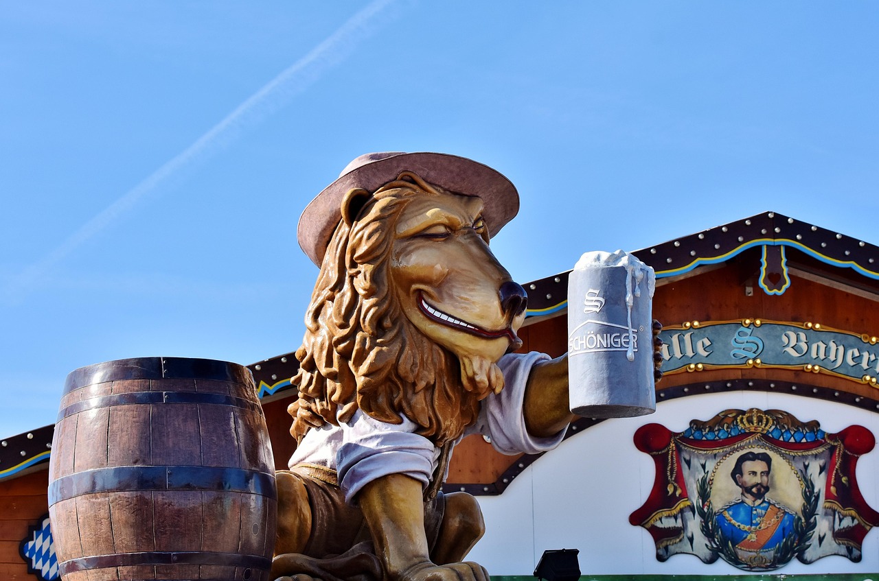 Decoração de festa com uma caneca de cerveja sobre um barril e uma figura de leão ao lado de uma tenda típica de Oktoberfest