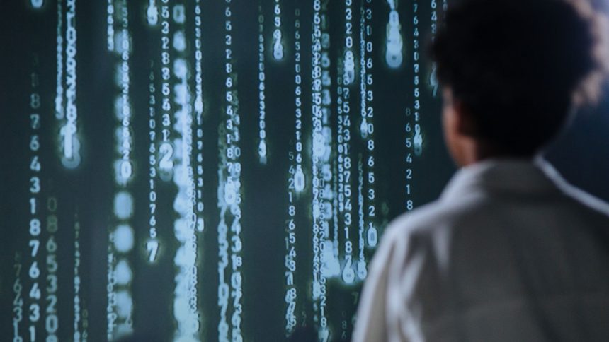 Pessoa observa números luminosos em uma tela, em representação de tecnologia e processamento de dados.
